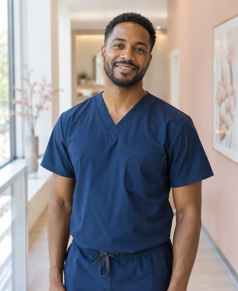 Tom Okafor, a nurse prescriber in navy scrubs, in the clinic corridor.