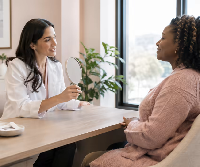A doctor explaining a treatment plan to a client with a hand mirror.
