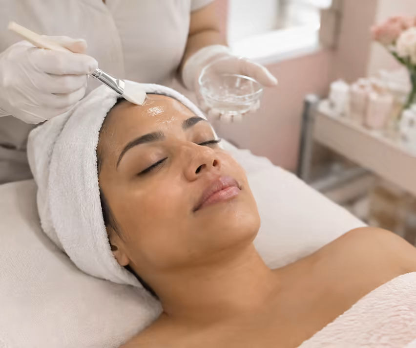 A client relaxing during a facial while serum is applied with a brush.