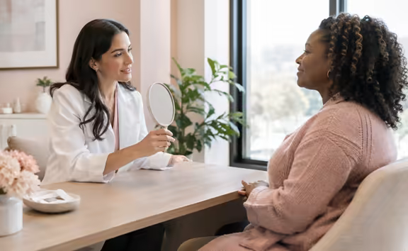 A doctor and a client talking across a consultation desk.